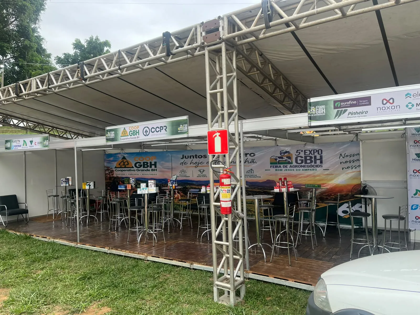 Estande da COOP GBH com mesas e painel da 5ª EXPOGBH
